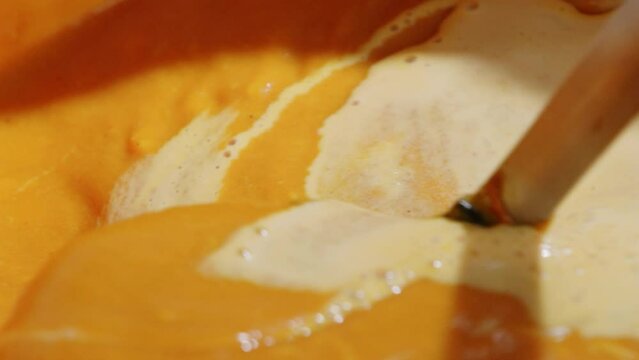 Stirring cream into tomato soup with a ladel