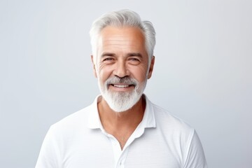 Handsome senior man. Portrait of a handsome senior man looking at camera and smiling while standing against grey background