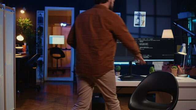 Developer arriving in apartment office with coffee mug in hand, ready to start coding on computer. IT specialist begins teleworking job shift, holding cup of tea, upgrading company software, camera B