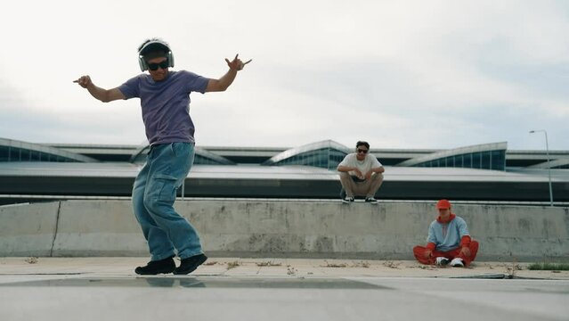 Group of asian break dancer perform street dance with multicultural friend support and moving hip hop music. Attractive handsome hipster practice b boy dance at street. Outdoor sport 2024. Sprightly.
