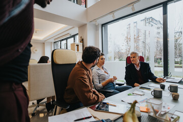 A different aged group of employees actively participating in a business meeting in a well-lit contemporary office setting, exchanging ideas and strategies. - Powered by Adobe