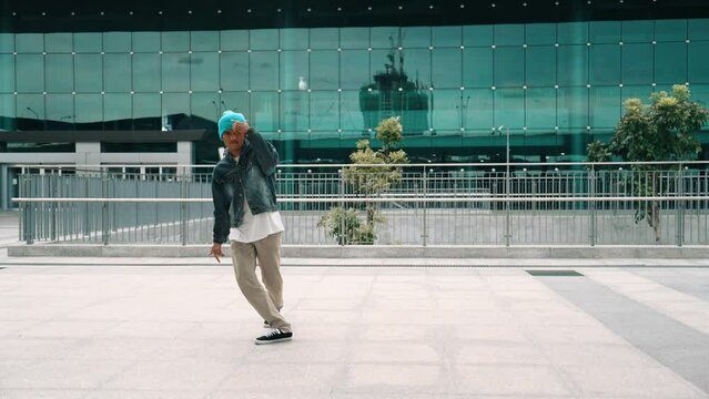 Happy hipster listen to hip hop music from headphone while dancing in lively mood. Professional street dancer perform b boy dancing at outdoor. Outdoor sport 2024. Modern lifestyle. Sprightly.