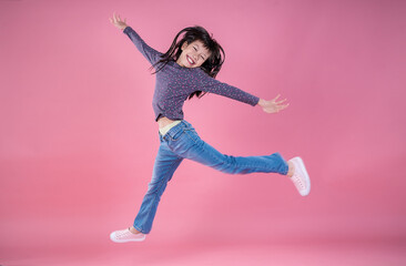 Portrait of young fun smart happy little asian jump and dance on pink background studio shot. Education for elementary kindergarten, little girl authentic back to school. Street trendy style.