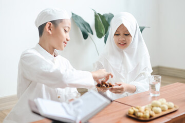 Young Asian muslim boy and girl having iftar or breakfasting together at home