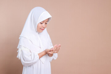 Cute Asian muslim little girl wear hijab, raising hands praying in Ramadan