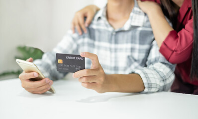 E-commerce Concept. Happy couple holding credit card enjoying doing online shopping and using laptop to enter their card number in-app to purchase and payment in the internet store