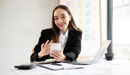 Asian businesswoman sit at their desks and calculate financial graphs showing results about their...