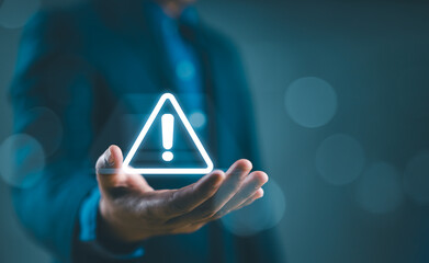 Businessman holding glowing of triangle caution warning exclamation sign for notification error and...