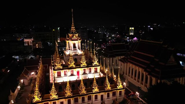 Aerial view of illuminated golden metal castle, Wat Ratchanatdaram Woravihara, Loha Prasat Temple at evening in Bangkok, Thailand