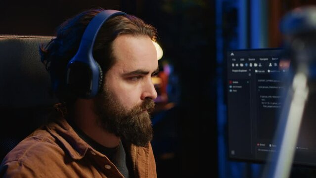 Developer listening music and drinking coffee while doing programming during remote job shift in home office. IT expert enjoying audio podcast and hot beverage, working on PC, camera A close up