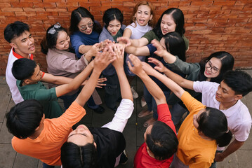 Group of happy friends high five and having fun together. Mixed race guys and girls celebrating...