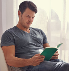 Happy man, relax and reading with book on chair in living room for story, literature or novel at home. Handsome male person or young adult with smile for information, knowledge or learning in leisure