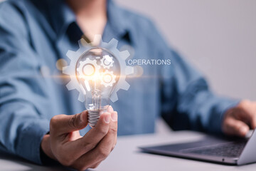 Operational concept. Businessman holding light bulb with operation icon for productivity with...