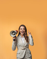 Obraz premium Happy young business woman in white suit holding megaphone isolated on yellow background. copy space