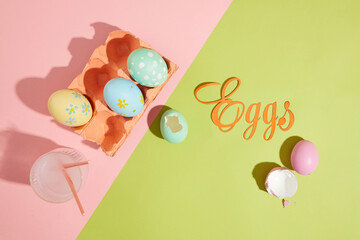 Some lovely Easter eggs contained inside an egg carton painted in coral color. A glass cup filled...