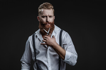 Barber using scissors isolated on black. Haircut from a hairstylist at a barbershop. Bearded Caucasian man hairdresser in hair salon. Hairstylist working in a hair salon. Trendy barbershop