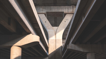 Geometric pattern background of concrete foundation structure of elevated expressway with light and shadow on surface, low angle view with copy space