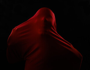 Scary, horror and person trapped in fabric for art and drama on black background in studio....