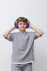 Teenage boy in a grey tracksuit listens to music that sounds through headphones