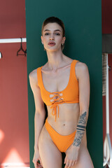 Fototapeta na wymiar young beautiful woman posing in an orange swimsuit in the studio