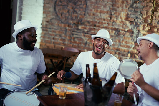 Band, men and play samba music while singing for carnival night, event and live performance with drums. Musicians, artists and beer for fun show in rio de janeiro, happy and celebration for parade