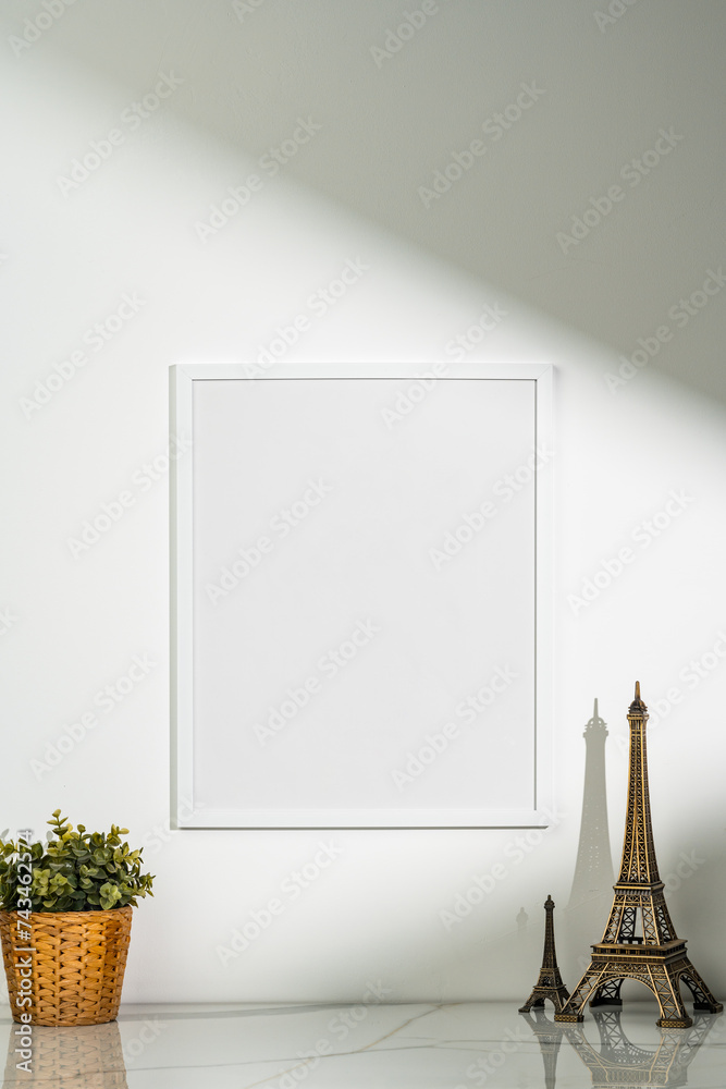 Wall mural Potted plant and blank picture frame against white wall