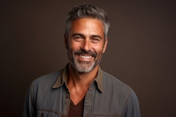 Portrait of a handsome middle aged man smiling against a dark background