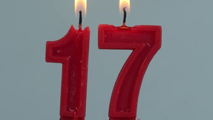 close up on timelapse melting a red number seventeenth birthday candle on a white background.
