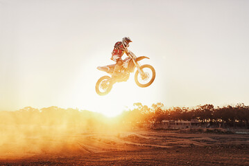 Person, jump and motorcyclist with sunset for trick, stunt or ramp on mockup or outdoor dirt track. Expert rider on motorbike in the air with lift off for extreme sports or rally challenge in nature