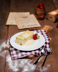 Cheesecake with strawberries on a plate, sunlit on a wooden table