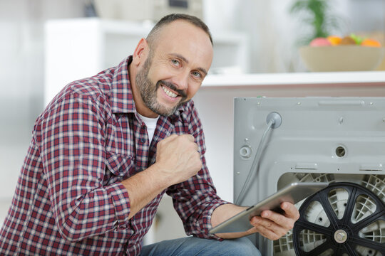 man using tablet pc to fix a washing machine