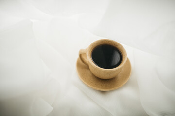 a cup of coffee stands on the windowsill with white curtains