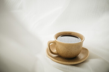 a cup of coffee stands on the windowsill with white curtains