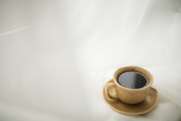 a cup of coffee stands on the windowsill with white curtains