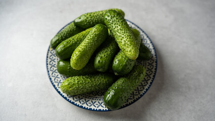 Fresh cucumbers on a plate, light gray stone background, banner, space for text
