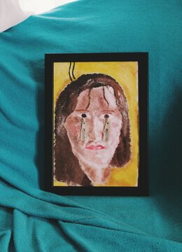 Photograph of a painting artwork of a crying woman with zips on face
