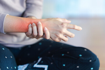 Woman with wrist pain or arm pain from heavy use on blurred background.