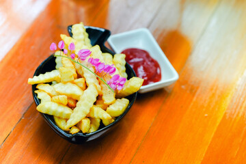 French fries in a white bowl on a beautifully decorated wooden table are served as appetizers in a restaurant.