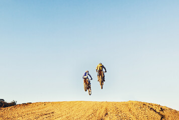 Rear view, racer and motorcycle in action for competition on dirt road with performance, challenge and adventure. Motocross, motorbike or dirtbike driver with jump stunt on offroad course for racing