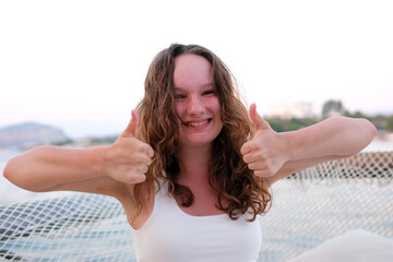 Image of happy young woman isolated over yellow background showing thumbs up gesture.