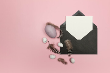 Top view of easter eggs, feathers, black envelope and white card on pink background. Creative easter composition, spring, flat lay, copy space.