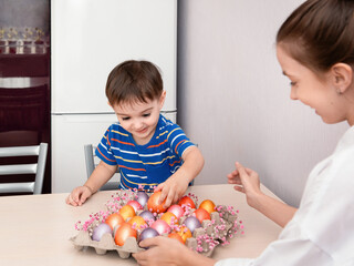 Children rejoice in the feast of Easter. A boy admires the beauty of colorful eggs. A girl shows beautiful colored eggs.