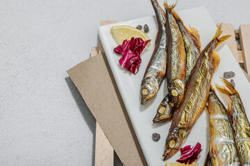 Smoked smelt with fresh lemon and herbs. Salted fish with marine decor. Trendy dish, sea rope