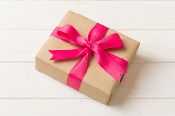 Wrapped christmas or other holiday handmade present in craft paper with colored ribbon. Present box, decoration of gift on table, top view with copy space