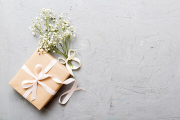Gift or present box and flower gypsophila on light table top view. Greeting card. Flat lay style...
