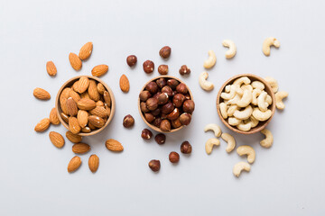 Assortment of nuts in wooden bowl on colored table. Cashew, hazelnuts, walnuts, almonds. Mix of nuts Top view with copy space