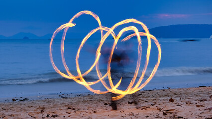 
An image depicts children engaged in fire dance play on the beach, their movements shaping various...