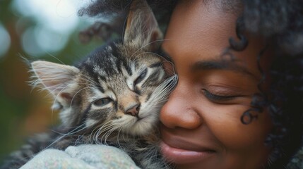 An animal shelter volunteer shows compassion and care by cuddling a kitten. - obrazy, fototapety, plakaty
