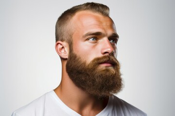 Obraz premium Portrait of a young Caucasian man with a neatly trimmed beard framing his jawline, against a clean, white background, highlighting the symmetry and definition of his facial hair