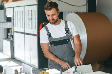 Smart engineer. Handsome man is working at the factory of creating eco boxes
